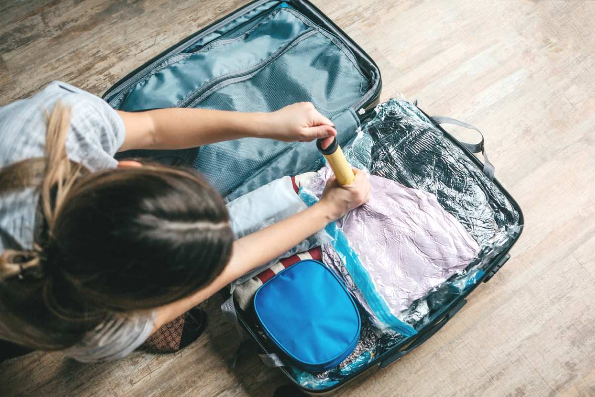 A girl uses a vacuum pump to clean her luggage in preparation for holiday travel. 